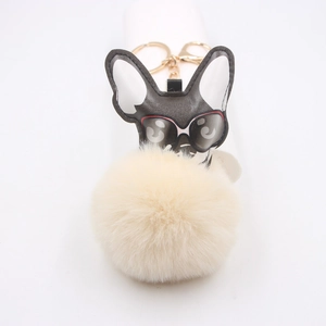 Détail d'un porte-clés chien cool avec lunettes de soleil et pompon en fourrure beige