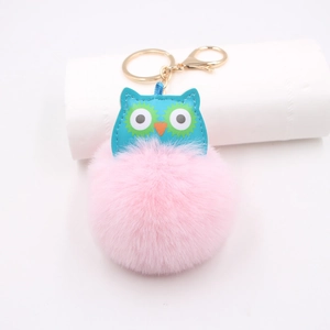Détail d'un porte-clés hibou rose moelleux avec similicuir bleu et fermoir en métal doré