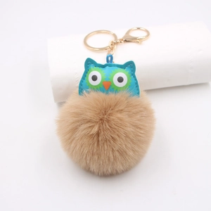 Détail du porte-clés hibou bleu avec une boule de fourrure marron et un fermoir doré