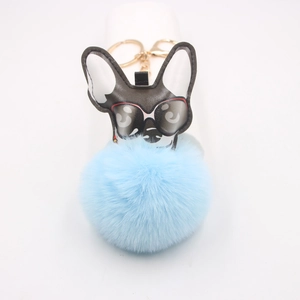 Détail d'un porte-clés bouledogue avec pompon bleu clair et fermoir en métal doré