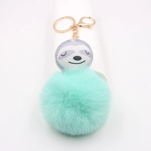 Détail d'un pendentif paresseux avec pompon en fourrure vert menthe et fermoir doré