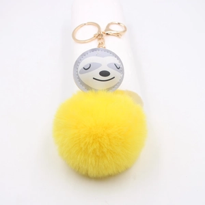 Gros plan sur le pompon jaune et le charme paresseux en similicuir avec porte-clés doré