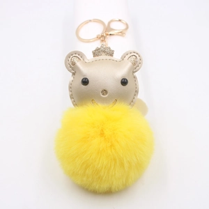 Détail d'un ours en cuir doré avec couronne scintillante et pompon jaune duveteux