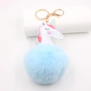 Close-up of light blue faux fur pompom and white unicorn charm with gold metal clasp