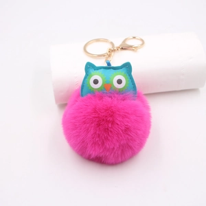 Détail du porte-clés hibou en fausse fourrure rose avec accents bleus et métal doré