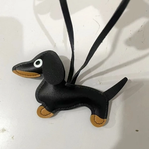 Detail view of a black leather dachshund bag charm with fine stitching and hanging strap