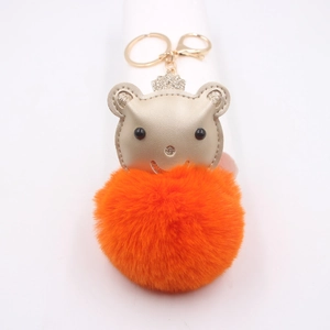 Détail du porte-clés ours à pompon orange avec couronne dorée et fermoir mousqueton