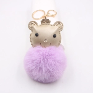 Détail du porte-clés ours doré avec grand pompon en peluche violette et couronne