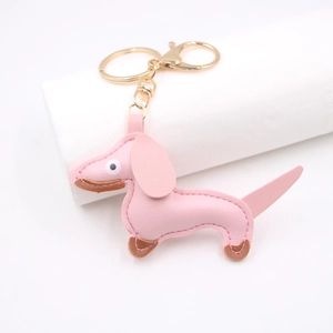 Pink PU leather dachshund dog keychain with golden lobster clasp on a white stand