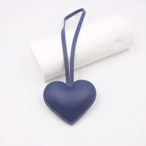 Close-up of blue heart-shaped leather bag charm with litchi grain texture and stitching