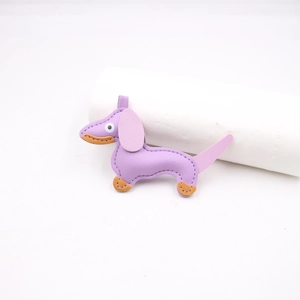 Dettaglio di un ciondolo bassotto in ecopelle viola con cuciture arancioni a contrasto