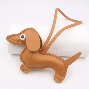Detailed view of caramel brown leather dachshund charm with litchi grain and hanging strap