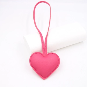 Detail of pink heart-shaped leather bag charm with stitching and long hanging strap