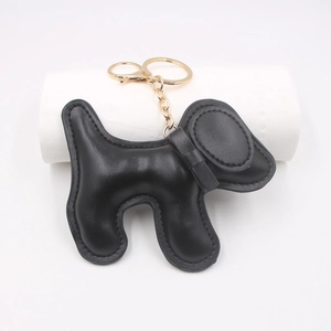 Detail view of a black padded leather dog charm with gold-tone metal keychain and snap hook