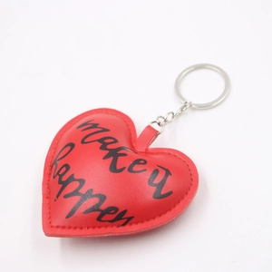 Close-up of red heart PU leather keychain with black make it happen printed quote
