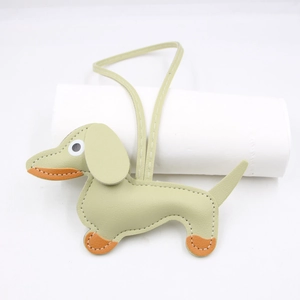Detail of dachshund bag charm in sage green leather with orange accents and white stitching