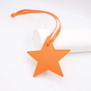 Macro detail of star-shaped orange leather bag pendant with yellow contrast stitching