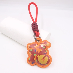 Dettaglio del ciondolo Fu in pelle arancione con pois colorati e corda intrecciata