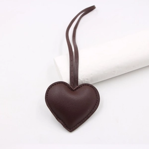 Detail of dark brown leather heart charm with lychee texture and fine stitching