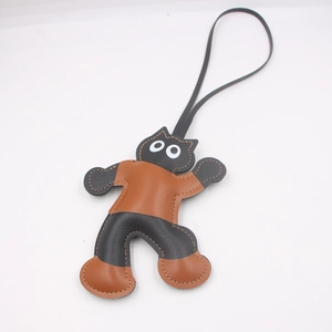 Detail of stitched leather bag charm with abstract character design and long strap