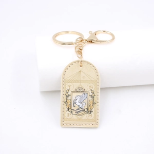 Close-up of arch-shaped beige PU leather keychain with gold ring and Pegasus emblem
