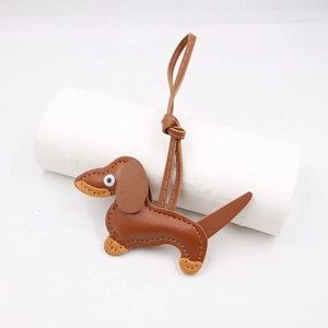 Detail of a brown leather dachshund keychain charm resting on a white paper roll prop