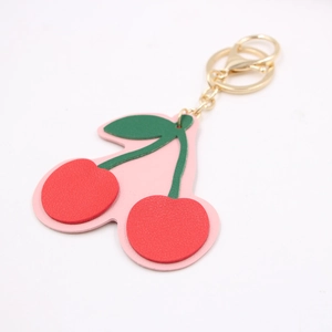 Handmade leather cherry keychain with red fruits and green leaves on gold metal ring