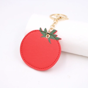 Red tomato PU leather keychain with green leaves and golden metal link on a white stand