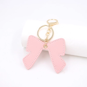 Pink faux leather bow keychain charm with elegant white stitching and gold lobster clasp