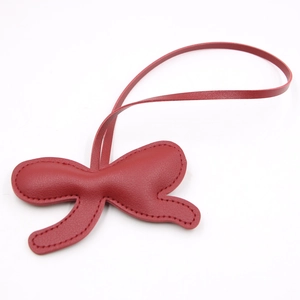 Detail of red leather butterfly charm with fine stitching and matching strap for bags