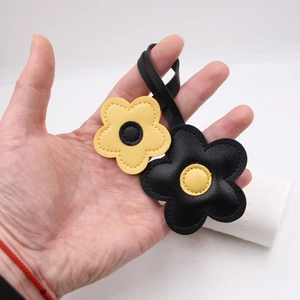 Detailed view of leather floral bag charm with yellow and black contrast stitching