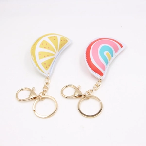 Dettaglio di ciondoli in pelle per borsa a forma di limone e arcobaleno con moschettoni