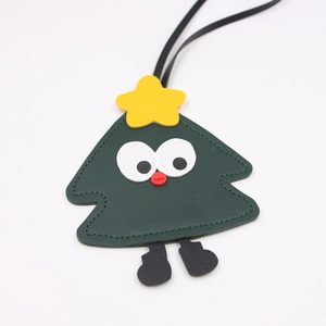 Close-up of a cartoon Christmas tree leather bag charm with yellow star and handmade stitching