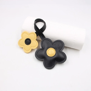 Detail of leather cherry blossom charms with fine stitching and black-yellow contrast