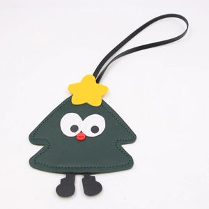 Close-up of cute Christmas tree bag charm with cartoon face and premium leather stitching