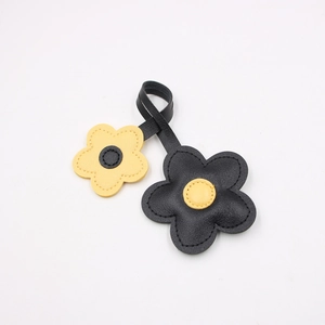 Detailed view of leather cherry blossom bag charm with black and yellow floral petals