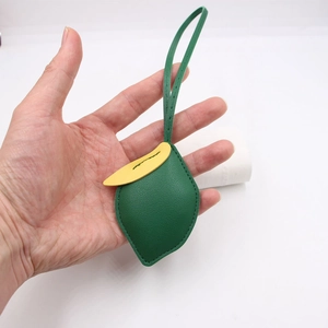 Detail eines Taschenanhängers aus grünem und gelbem Leder mit Nähten und langem Riemen