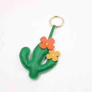 Close-up of green cactus leather charm with golden ring and floral details