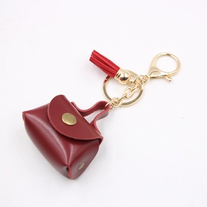 Dettaglio mini portamonete in pelle rossa con chiusura dorata e nappa decorativa