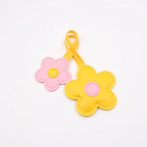 Macro detail of leather cherry blossom charms with yellow and pink floral stitching