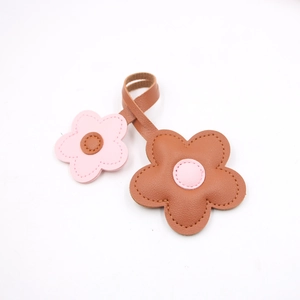Detailed view of pink and brown leather flower charm with decorative stitching details