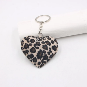 Macro shot of leopard print heart keychain with silver metal ring on white stand