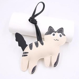Close-up of cute cow-patterned cat bag charm made of PU leather with neat white stitching