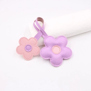 Detail shot of lilac and pink leather cherry blossom charms with precise edge stitching