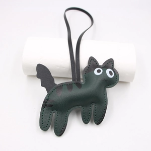 Macro detail of dark green faux leather cat charm with visible stitching and black spots