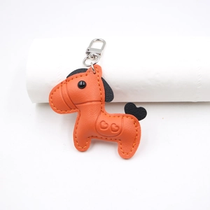 Detailed view of orange leather horse charm with heart embossing and silver lobster clasp