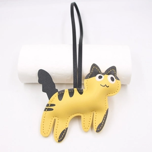 Detail view of yellow cat leather charm with black stripes and long strap attachment