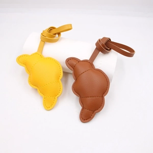 Ciondolo per borsa in pelle a forma di croissant con cuciture in giallo e marrone