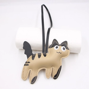 Detail of a handmade leather cat bag charm with fine stitching and khaki finish