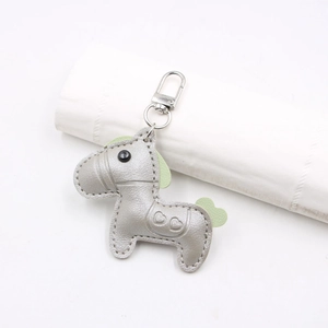 Close-up of a silver leather horse keychain with light green mane and heart saddle detail
